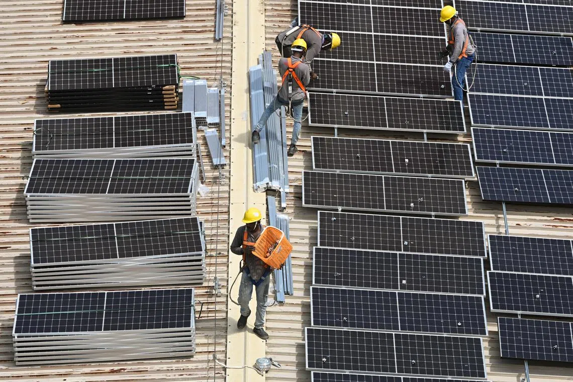 Workers installing solar panels on the rooftop of an HDB block in Tampines.