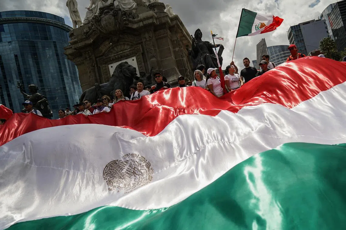 FILE PHOTO: Demonstrators display a large Mexico flag as they protest at the Angel of Independence after a highly contested judicial reform proposal was passed in the Senate in Mexico City, Mexico September 11, 2024. REUTERS/Toya Sarno Jordan/File Photo