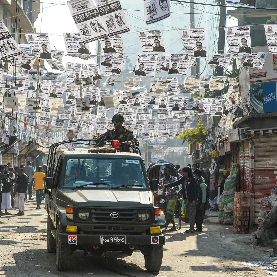 Bangladeshi army personnel drive through a street adorned with election posters near a polling station in Dhaka on Dec 30, 2018.