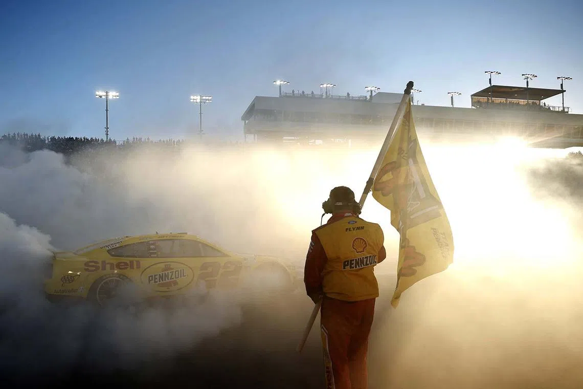 A crew member of the #22 Shell Pennzoil Ford waves the 2022 NASCAR Cup Series Championship flag as driver Joey Logano celebrates with a burnout after winning the 2022 NASCAR Cup Series Championship at Phoenix Raceway on Nov 6, 2022 in Avondale, Arizona., United States. 
