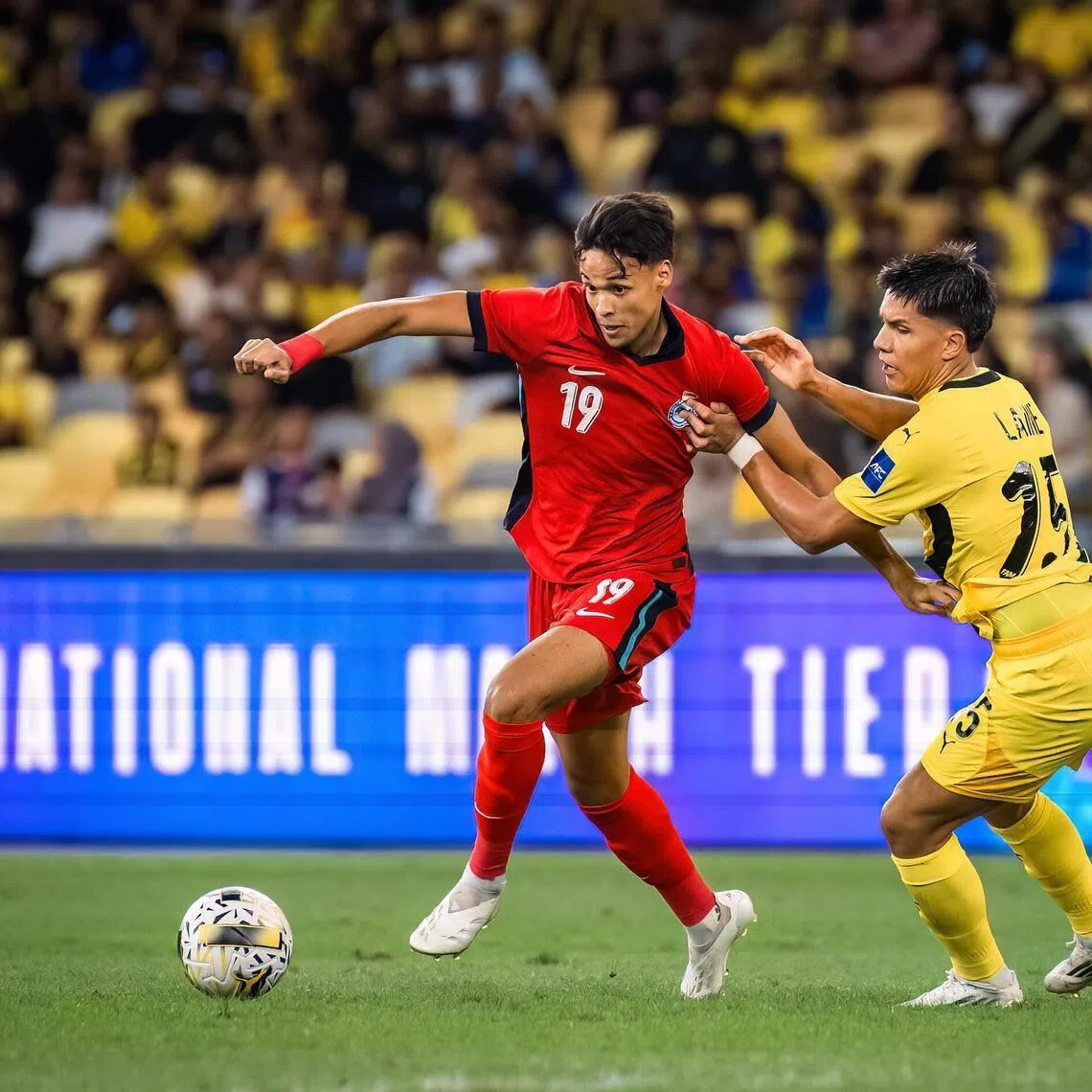 Singapore's Ilhan Fandi dribbling past Malaysia's Nooa Laine in a friendly in September 2025. He credits his Thai stint for sharpening his game.