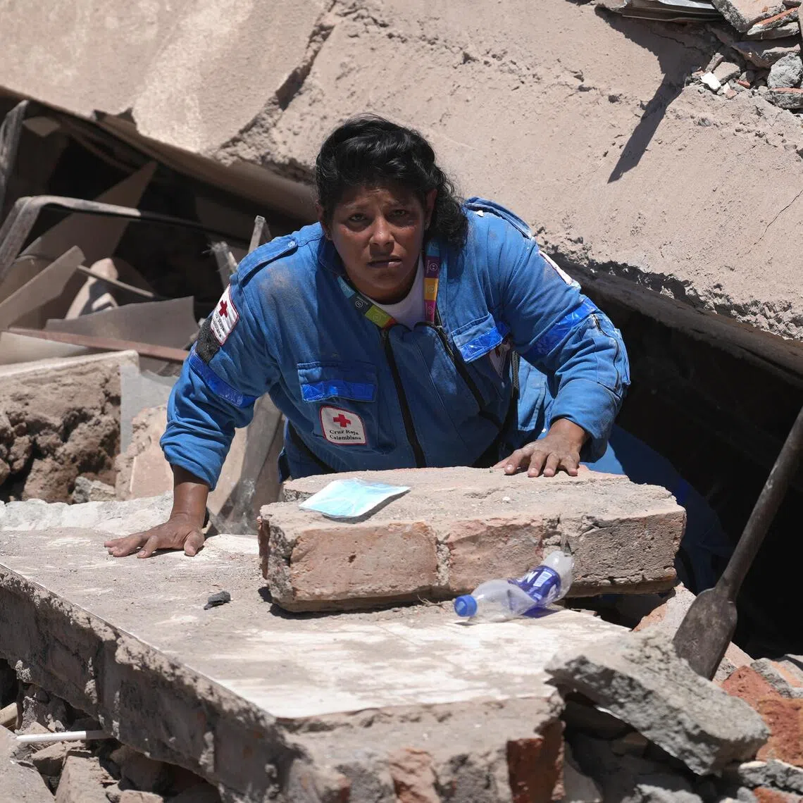 A member of the Colombian Red Cross searching through the rubble of a collapsed building in Cali, Colombia, after an Aug 10 earthquake.