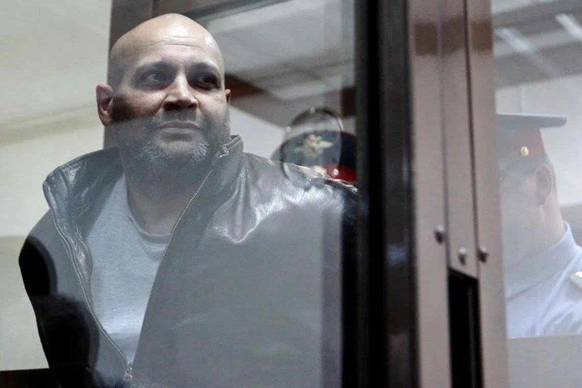 FILE PHOTO: One of the defendants in the murder trial of Russian journalist and human rights activist Anna Politkovskaya, Sergei Khadzhikurbanov is escorted into a glass-walled cage before a court hearing in Moscow, June 3, 2013. Politkovskaya was assassinated in October 2006. REUTERS/Maxim Shemetov/File Photo