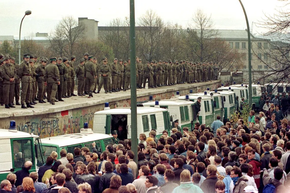 FILE PHOTO: Hundreds of East Berlin border guards stand atop the Berlin Wall at the Brandeburg Gate faced by thousands of West Berliners on November 11, 1989/File Photo