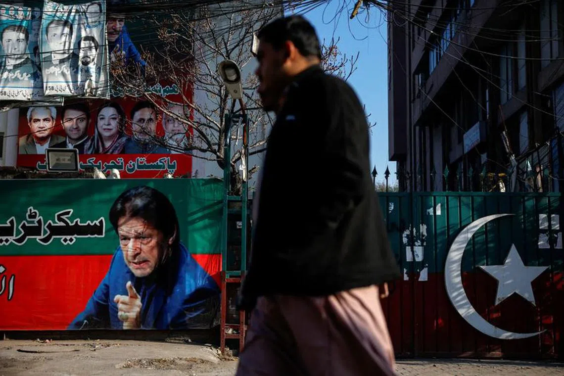 FILE PHOTO: People walk past a banner with a picture of the former Prime Minister Imran Khan outside the party office of Pakistan Tehreek-e-Insaf (PTI), a day after the general election, in Lahore, Pakistan, February 9, 2024. REUTERS/Navesh Chitrakar
