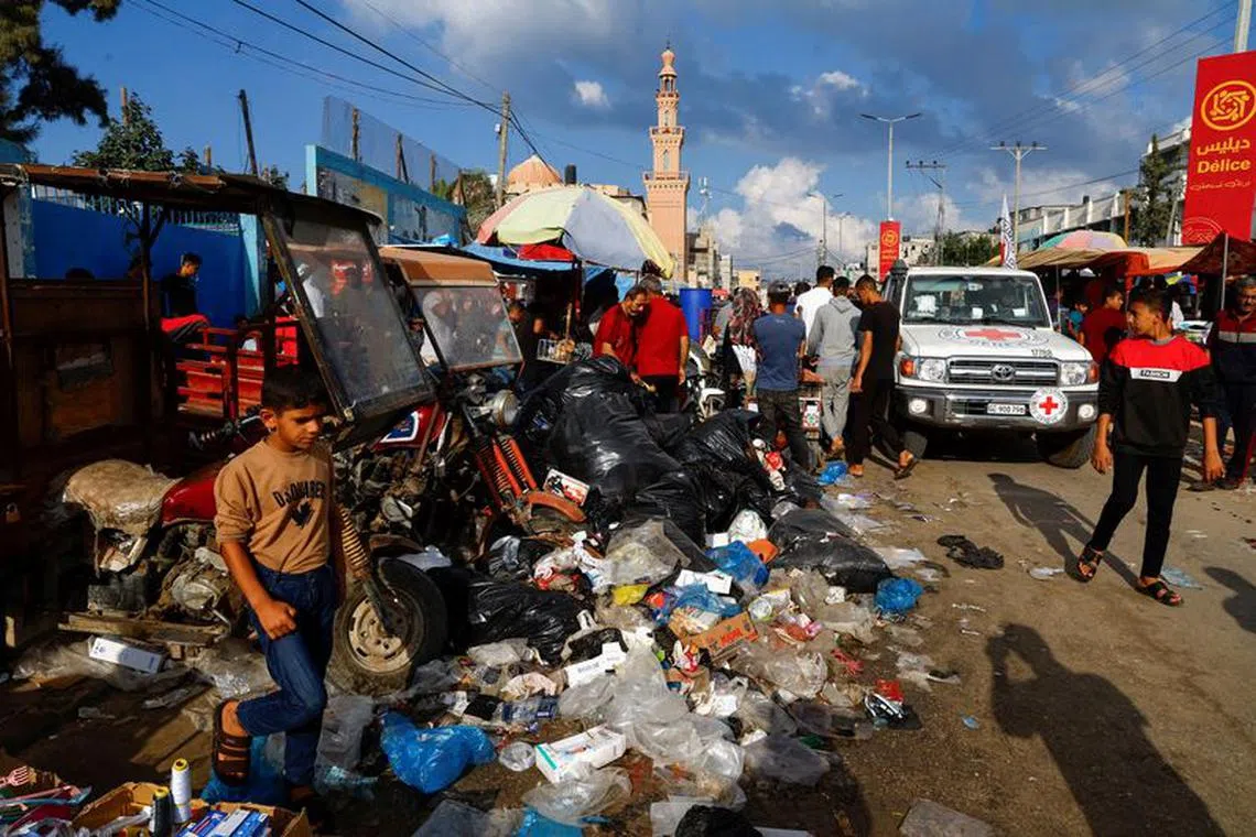 Palestinians walk past piles of garbage that threaten to spark an environmental catastrophe, amid the ongoing Israeli-Palestinian conflict, in Khan Younis in the southern Gaza Strip, October 16, 2023. REUTERS/Mohammed Salem