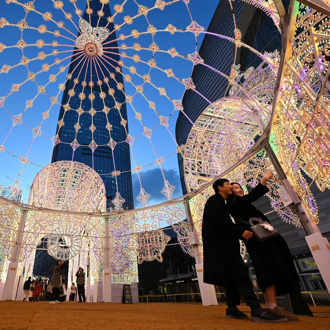 People taking photos in front of illuminated installations at the Lotte World Tower in Seoul on Feb 12, 2026.