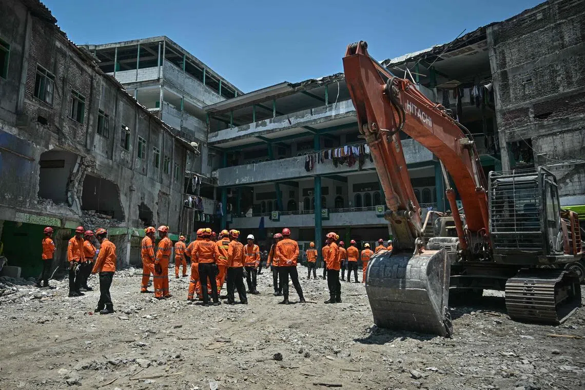 Rescue team members from the National Search and Rescue Agency gather after the end of debris removal and search operations at Al Khoziny Islamic boarding school in Sidoarjo, East Java, on Oct 7. 