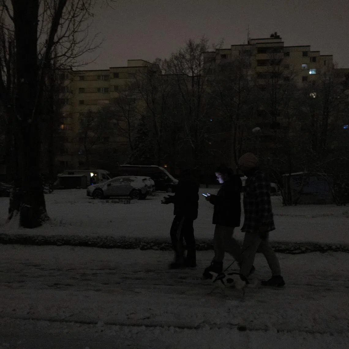 People walk through a darkened street during a blackout caused by a fire at a power distribution system in Berlin, Germany, January 3, 2026. REUTERS/Axel Schmidt