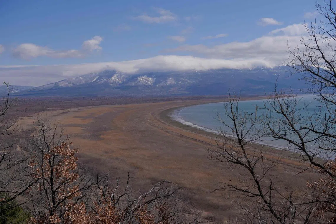 This photograph taken on March 17, 2023, shows a general view of the Prespa lake near Otesevo, in North Macedonia. - For millions of years Lake Prespa was pristine. But following decades of climate change, over consumption and pollution, the prehistoric body of water in southeast Europe is shrinking at an alarming rate. Straddling the borders of Albania, Greece and North Macedonia, Lake Prespa is believed to be home to thousands of species that rely on the water and its surrounding habitat.  But warming temperatures have wreaked havoc on the annual snowfall in the area, drying up vital streams that feed into Prespa, putting the species that depend on the lake and another nearby body of water at risk. (Photo by Armend NIMANI / AFP)