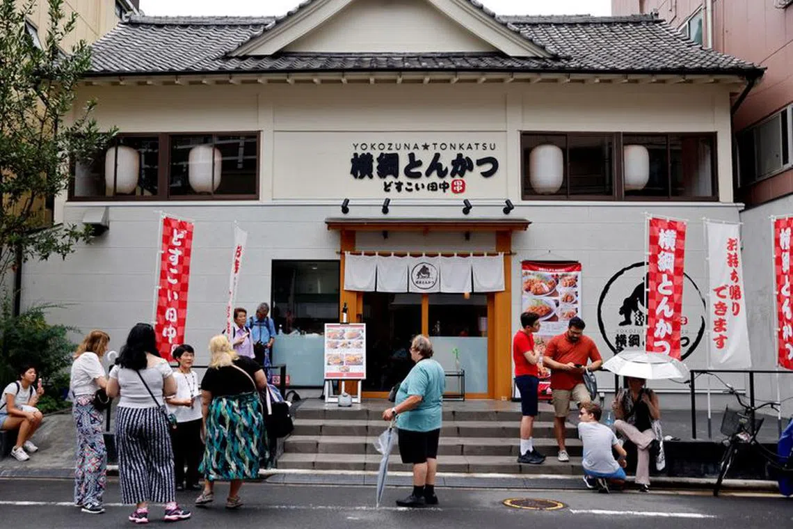 FILE PHOTO: Tourists from abroad wait for Yokozuna Tonkatsu Dosukoi Tanaka, a sumo wrestling themed restaurant to open, in Tokyo, Japan June 30, 2023.   REUTERS/Issei Kato/File Photo