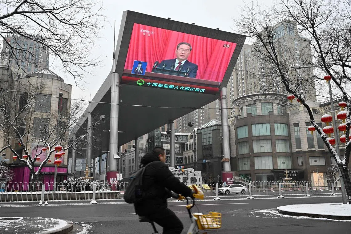 A screen shows Chinese Premier Li Qiang delivering a work report during the opening session of the National People’s Congress (NPC) at the Great Hall of the People, in Beijing on March 5, 2026. (Photo by ADEK BERRY / AFP)