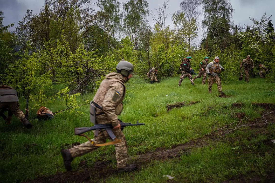 Ukrainian servicemen run to take cover during shelling near the frontline city of Bakhmut in Ukraine on April 30.