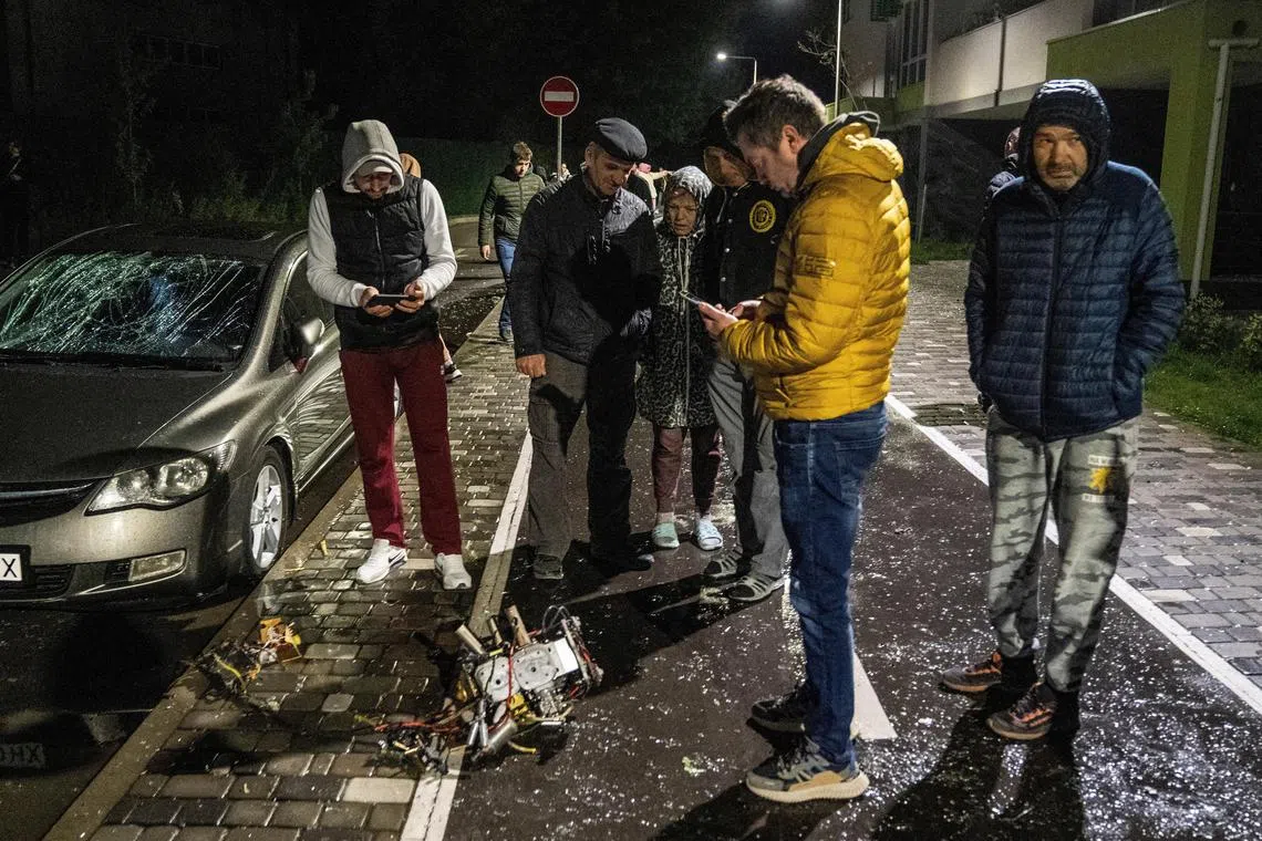 Local residents inspecting a part of a suicide drone, which local authorities consider to be Iranian made unmanned aerial vehicles (UAVs) Shahed-131/136, shot down during a Russian overnight strike, amid Russia's attack on Ukraine, in Kyiv, Ukraine May 8, 2023. 