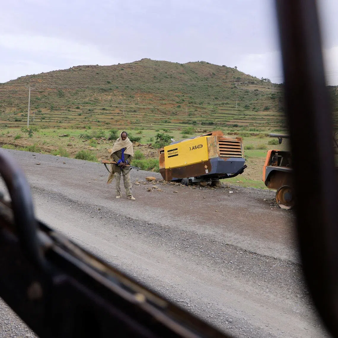 A Tigrayan Militia member stands next to construction machinery destroyed during the fighting between the Tigray People's Liberation Front (TPLF) and Ethiopian National Defence Force (ENDF) allied with Amhara Special Forces and Eritrean Defence Forces (EDF) on the outskirts of Samre, Tigray Region, Ethiopia, June 23, 2023. REUTERS/Tiksa Negeri
