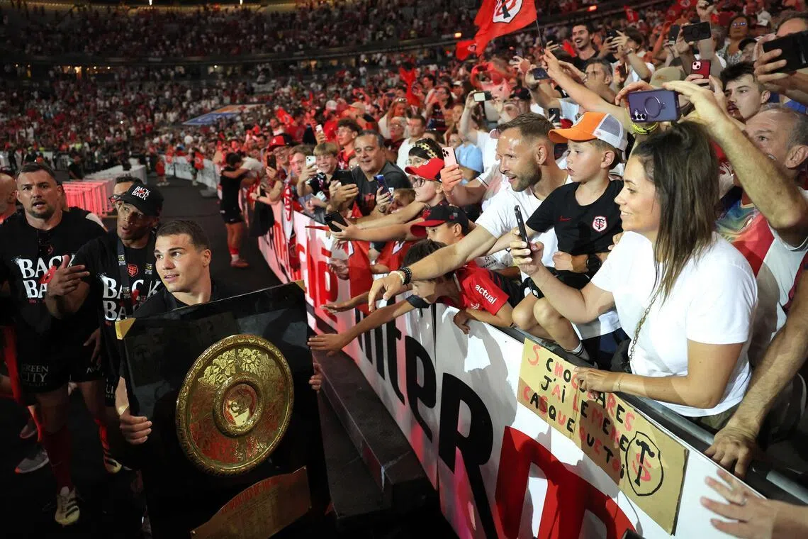 Toulouse's French scrum-half Antoine Dupont brings the "Bouclier de Brennus" trophy to supporters after winning the French Top 14 rugby union final against Montpellier Hérault Rugby (MHR) at the Stade de France in Saint-Denis, on the outskirts of Paris, on June 27, 2026. (Photo by Kenzo TRIBOUILLARD / AFP)