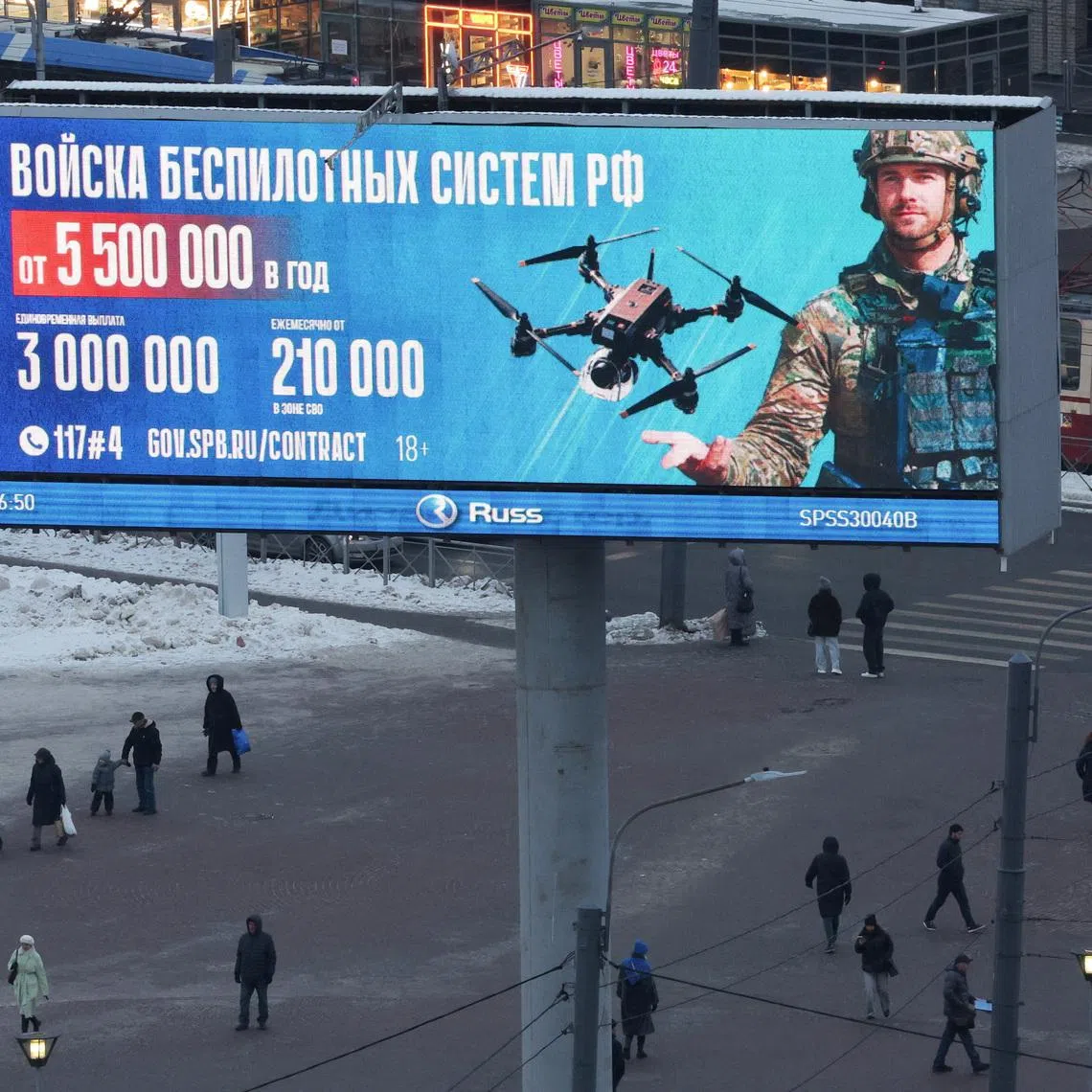 FILE PHOTO: People walk under a digital screen displaying an ad promoting contract military service in the Russian army’s unmanned systems forces, with payment details and contact information, in Saint Petersburg, Russia, January 26, 2026. REUTERS/Anton Vaganov/File Photo