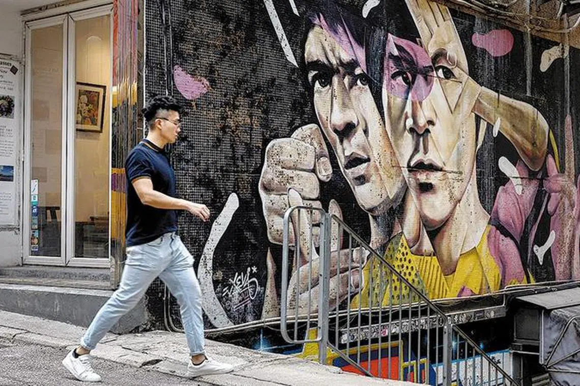 A man walks past graffiti of late kung fu star Bruce Lee in Hollywood Road in Hong Kong's Sheung Wan area on May 5, 2023. 