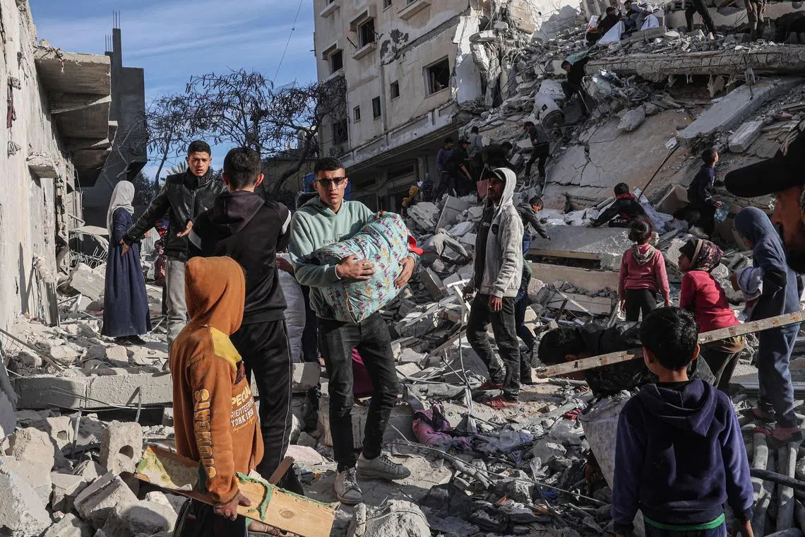 A Palestinian youth walks away with some items salvaged from the rubble of a residential building hit in an overnight Israeli air strike, in Rafah, in the southern Gaza Strip.
