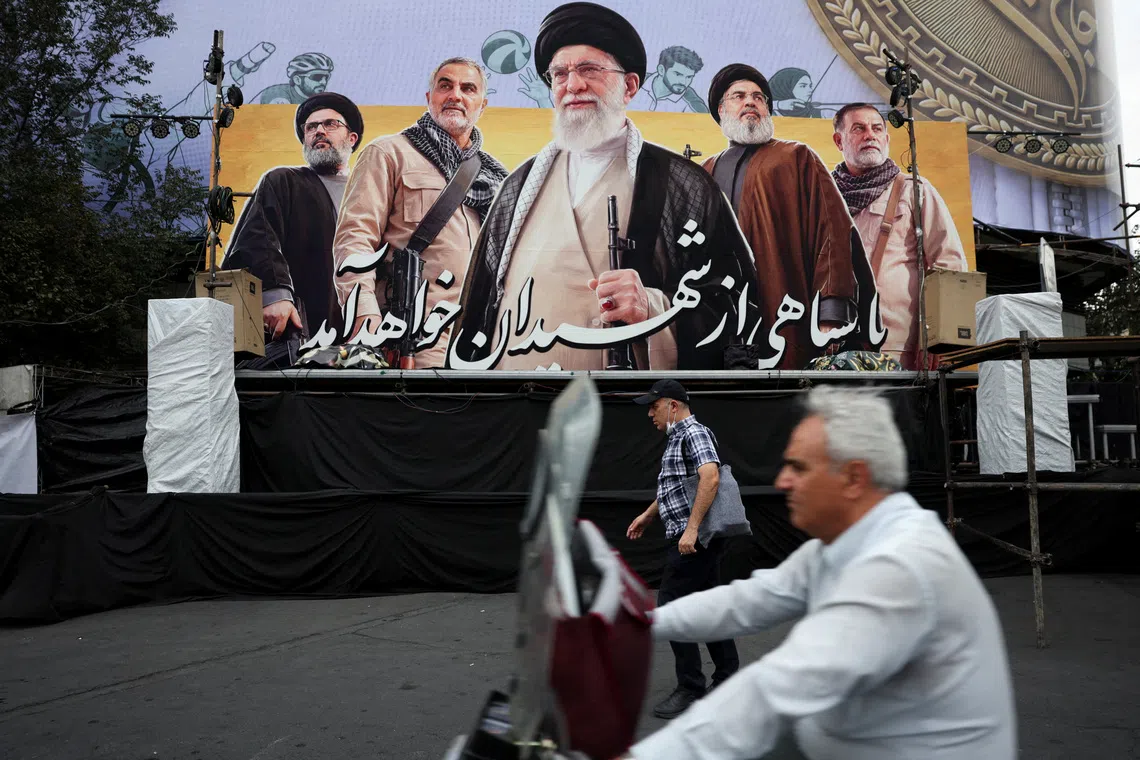 FILE PHOTO: A man walks past a bilbord depicting Iran's late Supreme Leader Ayatollah Ali Khamenei, the late former Hezbollah leader Hassan Nasrallah and the late military commander Qassem Soleimani, on a street in Tehran, Iran, October 6, 2026. Majid Asgaripour/WANA (West Asia News Agency) via REUTERS