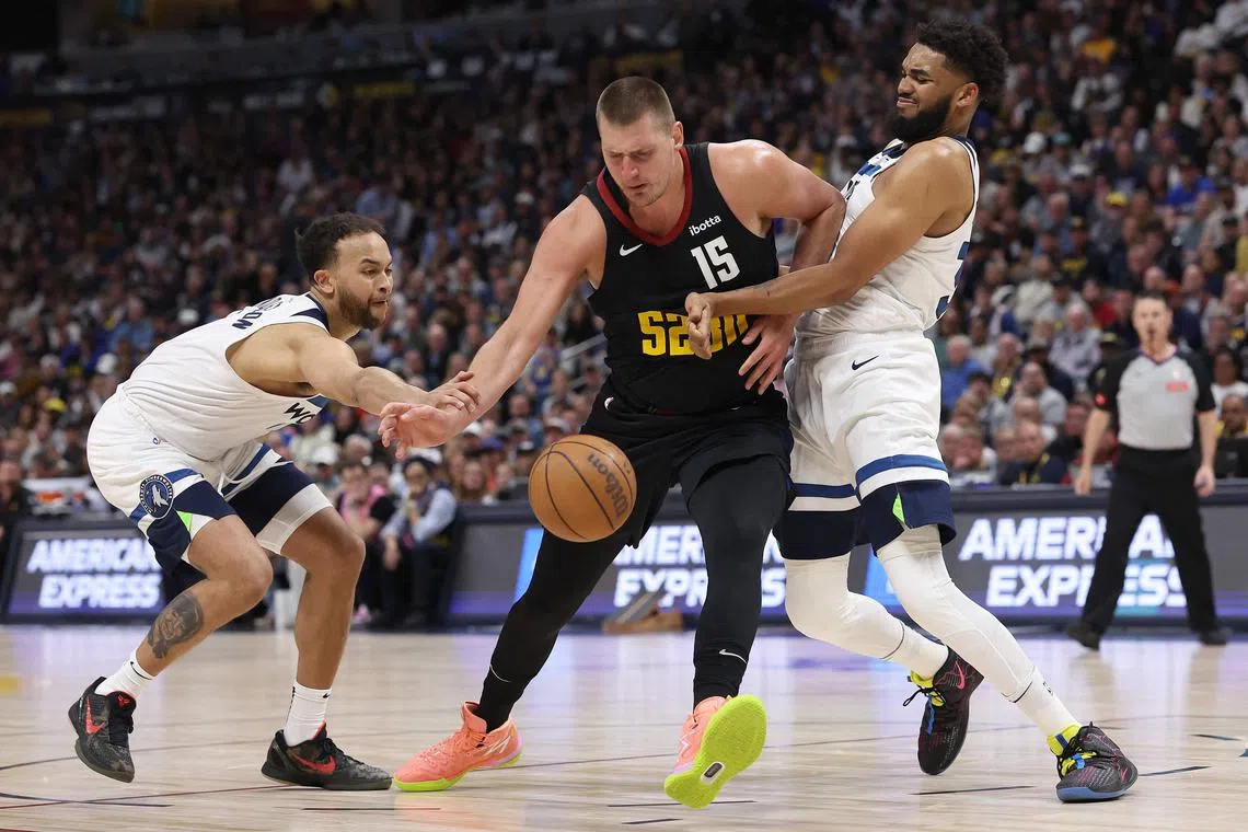 Nikola Jokic of the Denver Nuggets is fouled driving against Kyle Anderson and Karl-Anthony Towns of the Minnesota Timberwolves during Game 2 of the NBA Western Conference semi-finals.