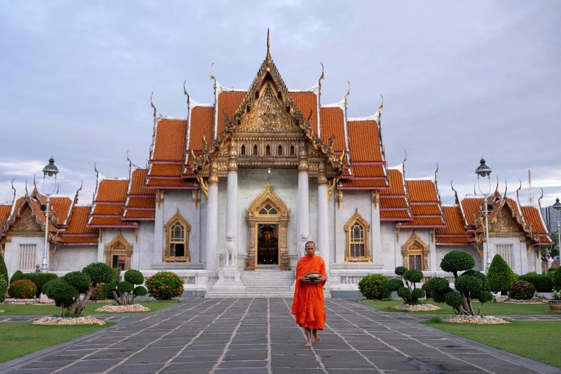 A Buddhist monk prepares to collect alms in front of a temple in Bangkok on July 18, 2025.