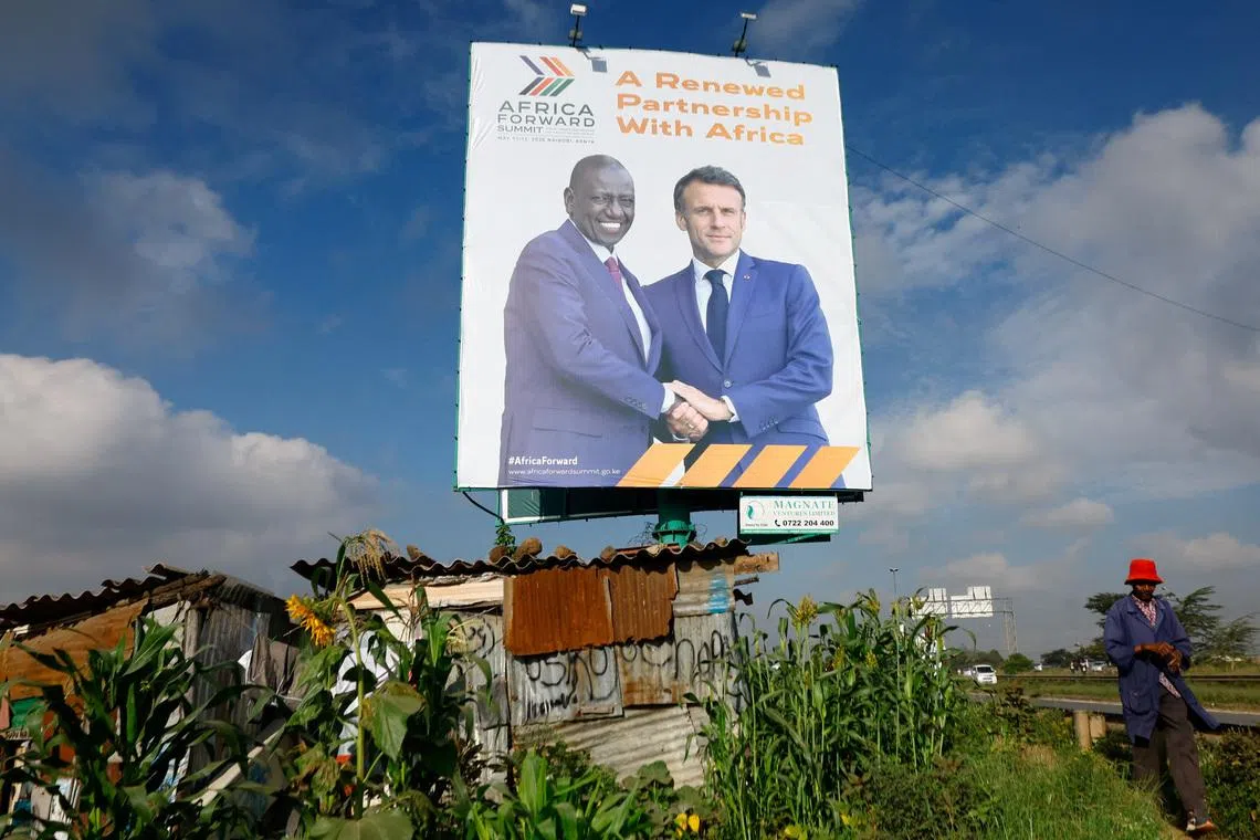 A pedestrian walks near a billboard featuring Kenyan President William Ruto and French President Emmanuel Macron ahead of the \"Africa Forward\" Summit, in the outskirts of Nairobi, Kenya May 7, 2026. REUTERS/Thomas Mukoya