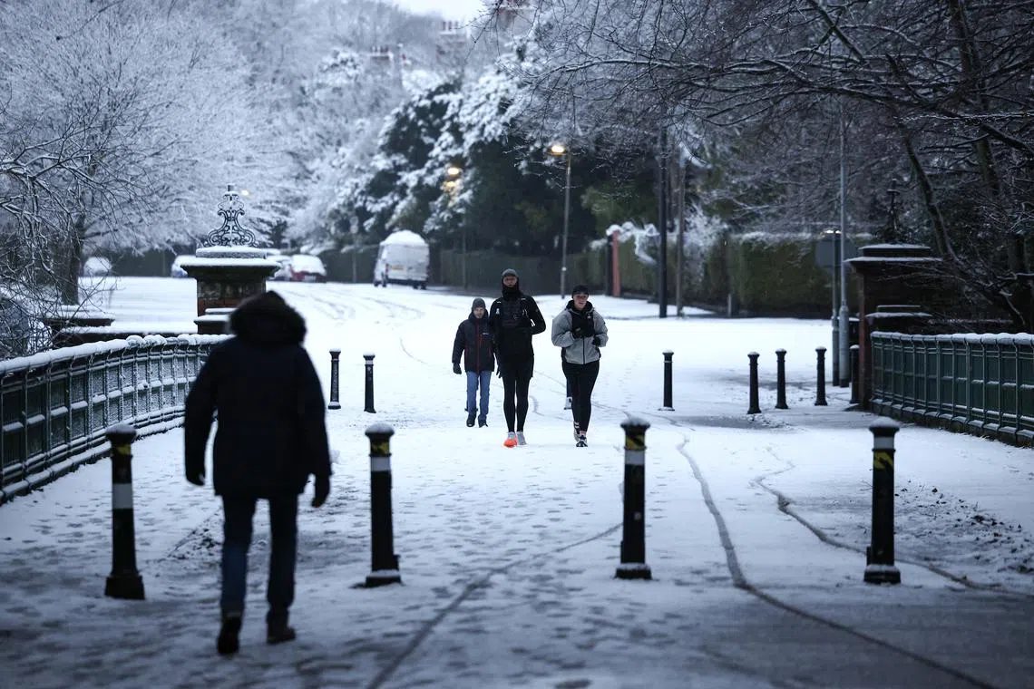 People walk in the snow at Sefton Park in Liverpool on Jan 5.