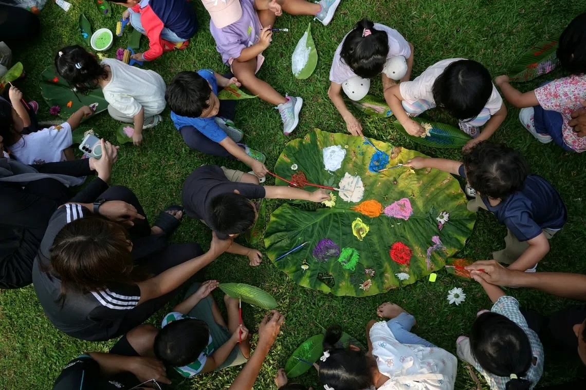 Children paint on leaves and decorate them before hanging their works of art out to dry during an outdoor playdate organised by Madam Nurul Aqilah Zakaria.