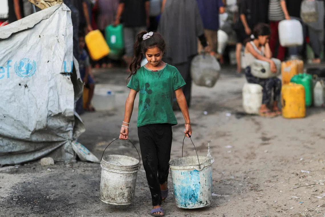 A Palestinian girl carries buckets of water amid shortages, in Gaza City August 6, 2025. REUTERS/Mahmoud Issa