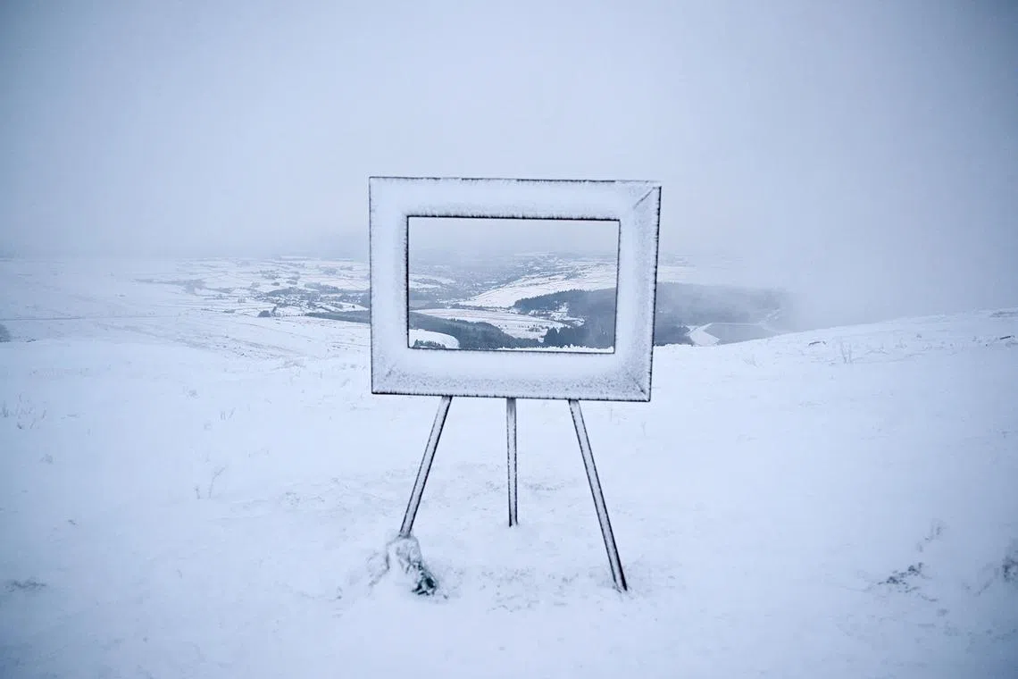 Fog and snow surround an art installation, giving a pictured-framed view over the valley beneath, at the summit of Holme Moss in the Peak District, in northern England on Jan 7, 2025, after snow and rain continued to fall across parts of the United Kingdom. 