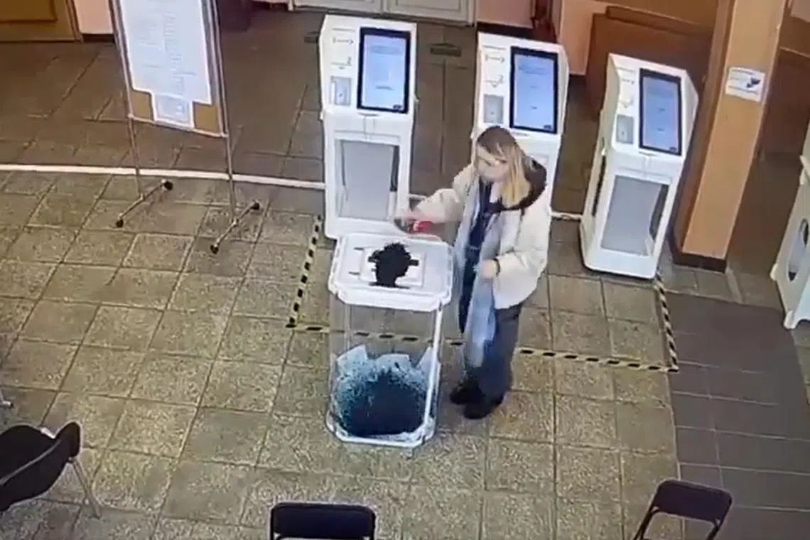 A woman pours dye or ink into a ballot box in Russia, in a screen grab from a social media video.