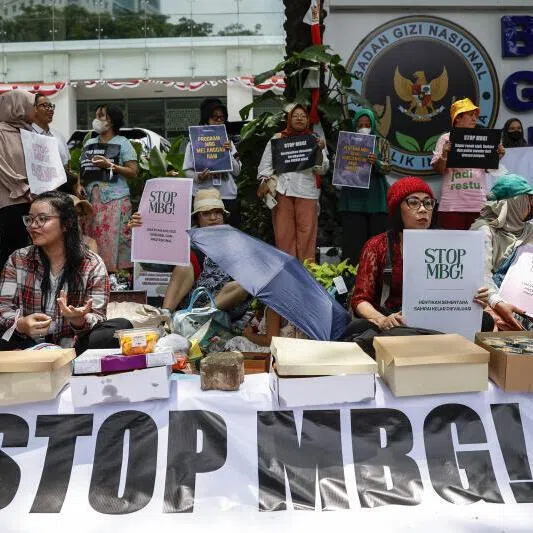 Protesters hold placards outside the National Nutrition Agency building during a rally demanding an end to the government's free nutritious meal (MBG) program, following cases of food poisoning in schools, in Jakarta, Indonesia, October 15, 2025.