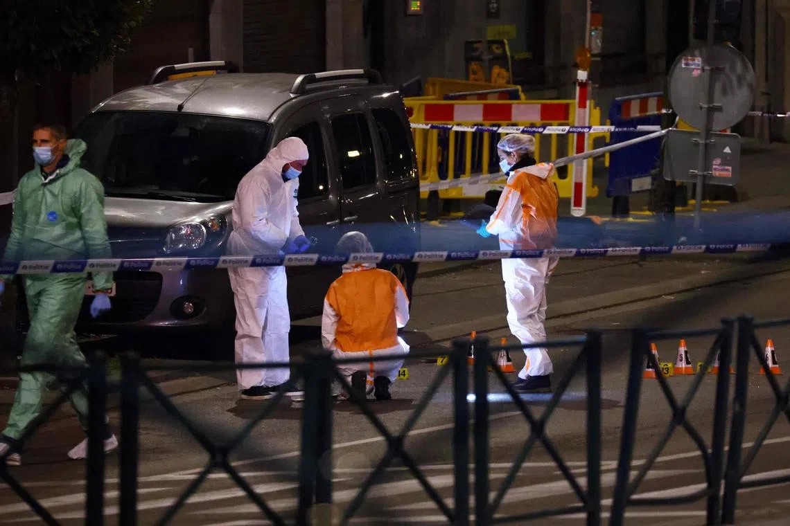 Belgian police officers from the forensic service search for evidence in a street after two people were killed during a shooting in Brussels on Monday.