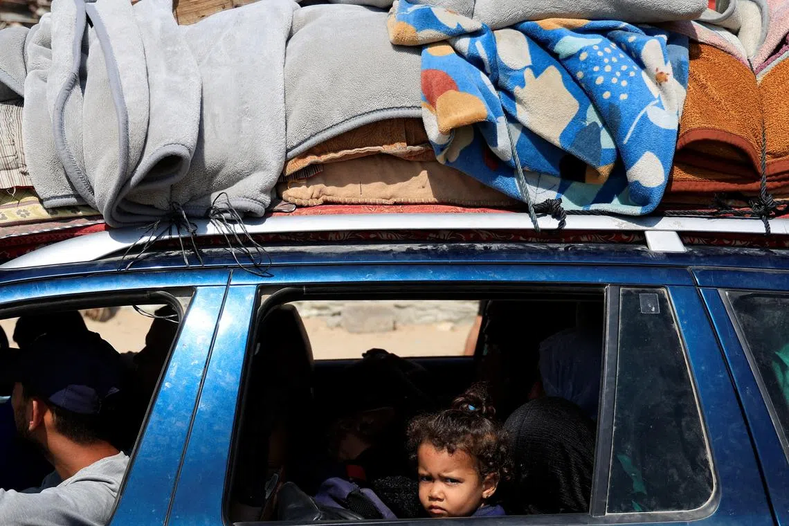 A child looks on as Palestinians carry their belongings as they flee their homes after the Israeli army issued evacuation orders, in Khan Younis, in the southern Gaza Strip, June 3, 2025. REUTERS/Hatem Khaled
