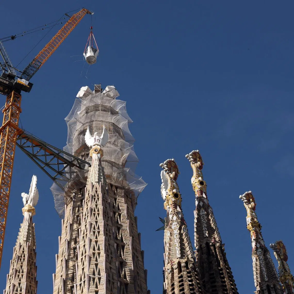 A crane lifts the final piece of the 17m cross that completes the Sagrada Familia's Tower of Jesus Christ.
