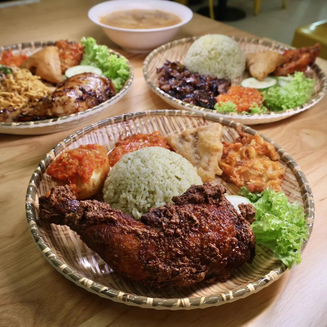 Clockwise from front: Coriander Fried Chicken With Signature Lime Rice, Grilled Chicken With Indomie, Sayur Asem Soup and Grilled Lamb With Signature Lime Rice at Palapa Indonesian Fast Food.
