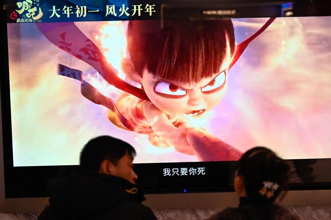 People wait as a screen displays a scene from the Ne Zha 2 animated film at a movie theatre in Beijing on February 16, 2025. Chinese blockbuster "Ne Zha 2" has ousted Disney's "Inside Out 2" to become the highest-grossing animated film of all time, state media reported February 18, citing a domestic ticketing platform. (Photo by Pedro PARDO / AFP)