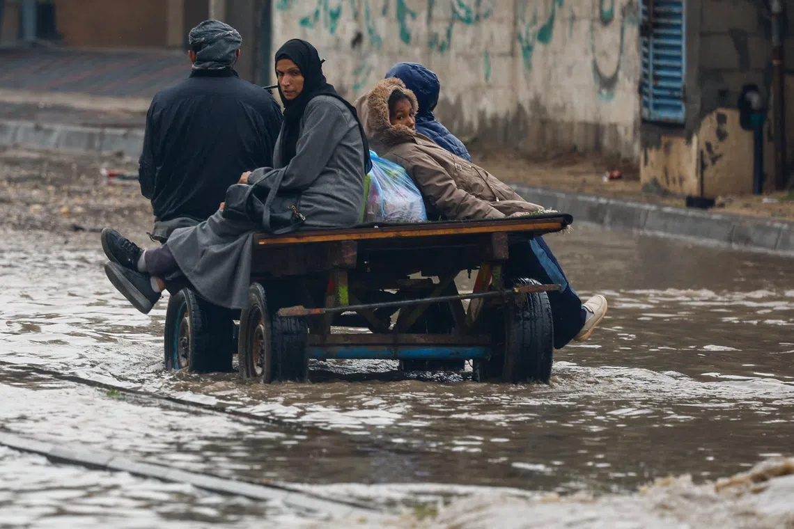 Displaced Palestinians make their way through a flooded street on a cart, during a rainy day in Nuseirat, central Gaza Strip, December 11, 2025. REUTERS/Mahmoud Issa