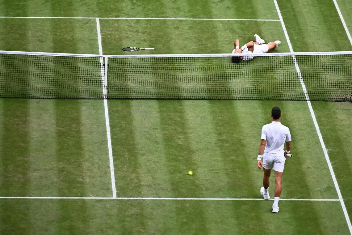 Spain's Carlos Alcaraz falls down in delight after passing the Djokovic test at Wimbledon. 
