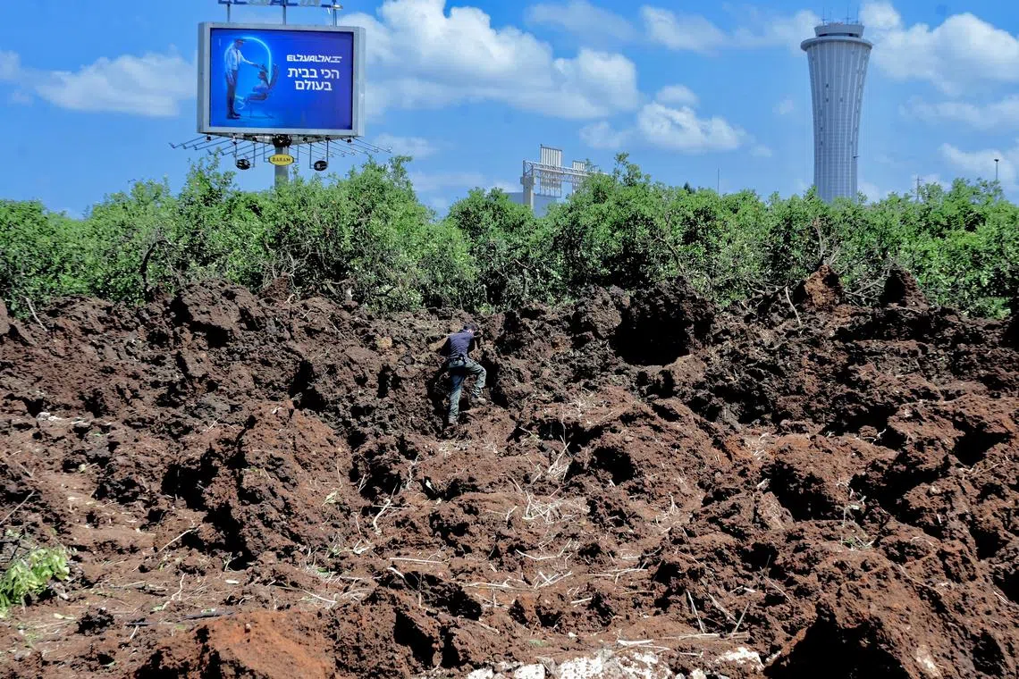 An Israeli police officer investigates a crater at the site of a missile attack, launched from Yemen, near Ben Gurion Airport, in Tel Aviv, Israel May 4, 2025. REUTERS/Avshalom Sassoni