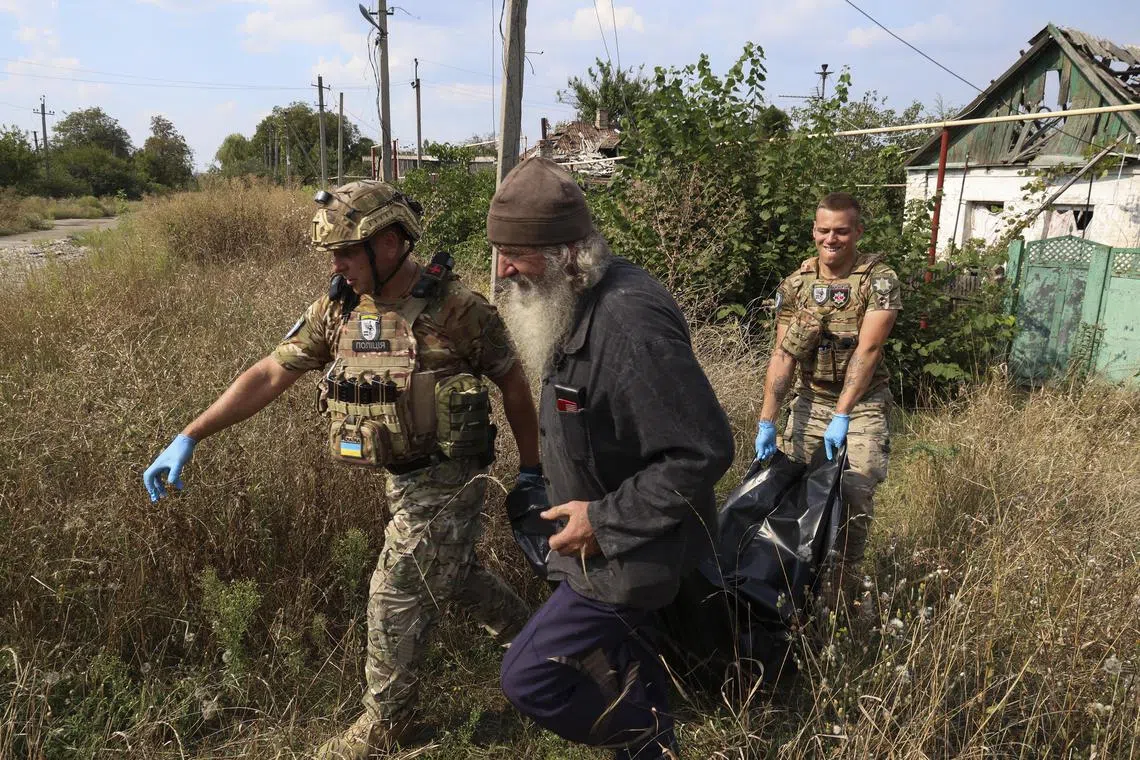 Police officers and a local resident carry the body of an elderly man who committed suicide, in the front-line settlement of Avdiivka, Ukraine.