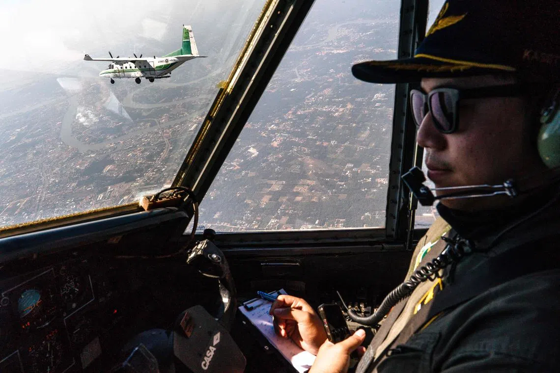 TOPSHOT - This photo taken on January 15, 2024 shows a pilot flying next to another aircraft from Thailand's Royal Rainmaking department taking part in an atmospheric modification mission to displace pollution by spraying icy water in the air on the outskirts of Bangkok. Flying some 5,000 feet high through cloudless blue skies, a small aircraft sprays a white mist over a thick haze of pea soup smog below. This is Thailand's desperate, unproven attempt at reducing the oppressive air pollution over Bangkok -- which on January 22 reached seven times the World Health Organization's recommended daily maximum average. (Photo by Chanakarn Laosarakham / AFP) / TO GO  WITH: THAILAND-ENVIRONMENT-POLLUTION, FOCUS by Sally JENSEN and Watsamon TRI-YASAKDA