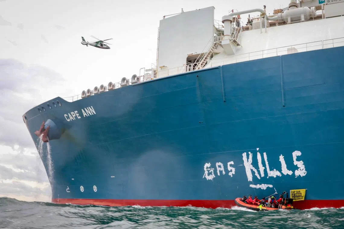 Greenpeace France activists scrawling the words 'Gas Kills' on the side of the TotalEnergies Cape Ann LNG terminal, anchored off the northern French port city of Le Havre, in the English Channel on Sept 18.