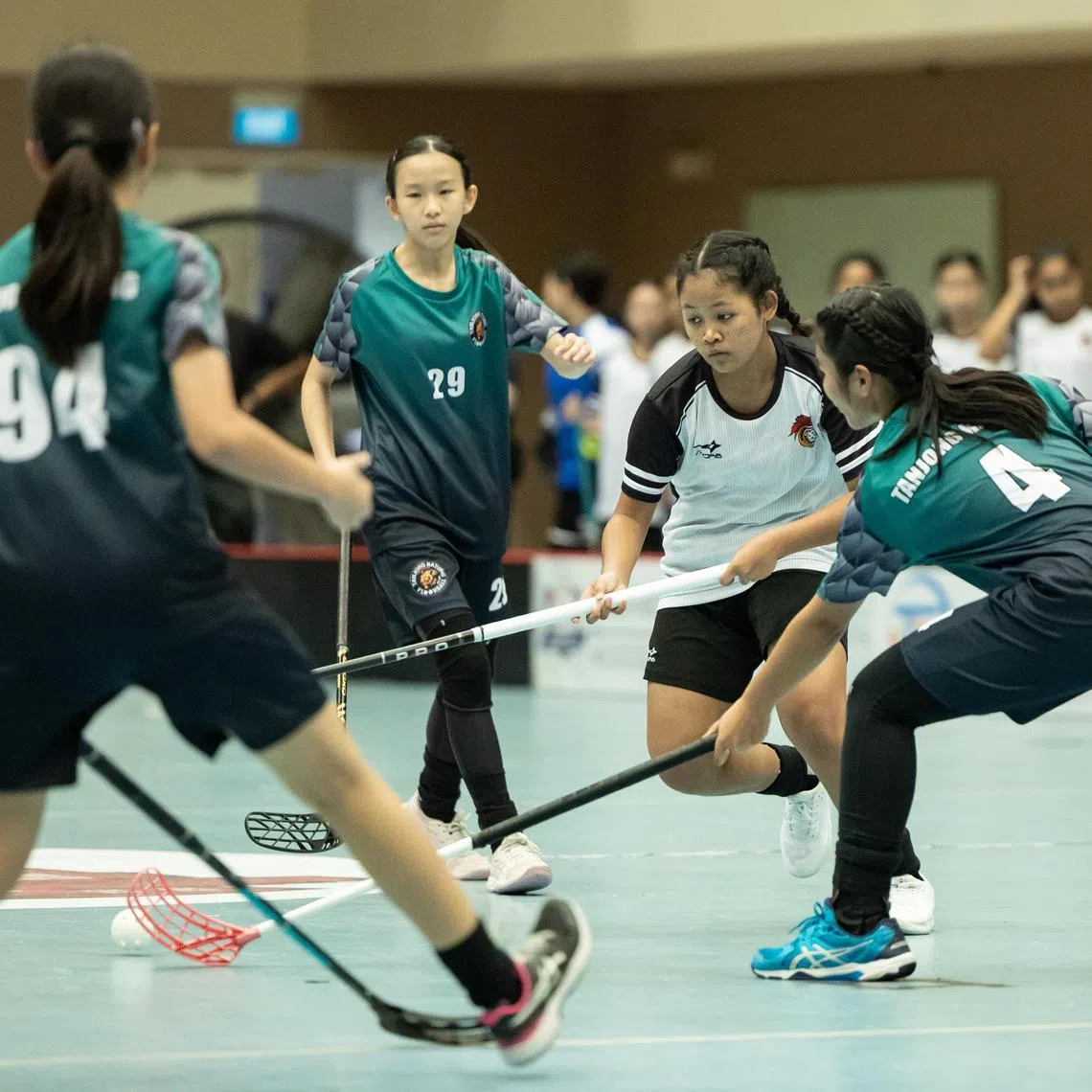 St Hilda's Secondary School's Nur Anniqa Irtysha Muhammad Rafie (second from right) in action against Tanjong Katong Secondary School during the girls' C Division floorball final on Sept 2.