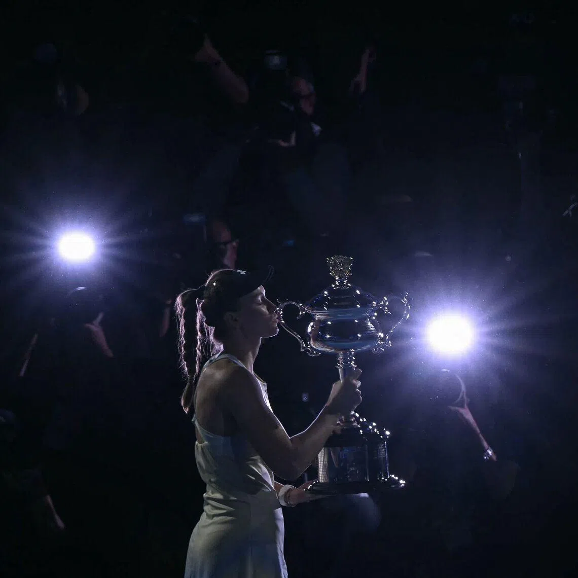 TOPSHOT - Kazakhstan's Elena Rybakina kisses the winning trophy after her victory against Belarus' Aryna Sabalenka in the women's singles final match on day fourteen of the Australian Open tennis tournament in Melbourne on January 31, 2026. (Photo by WILLIAM WEST / AFP) / -- IMAGE RESTRICTED TO EDITORIAL USE - STRICTLY NO COMMERCIAL USE --