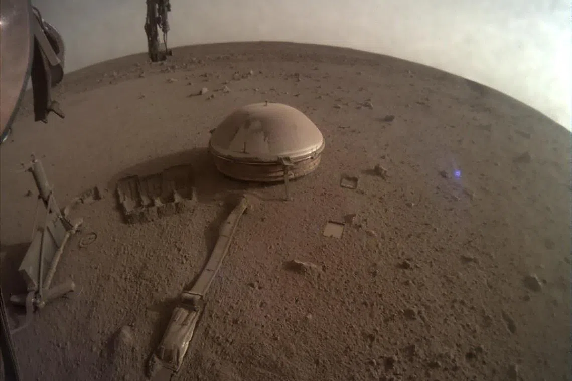 In this image provided by Nasa/JPL-Caltech, one of the Mars InSight lander's last images shows its seismometer resting on the Martian surface on Dec 11, 2022. After four years of making important discoveries about the interior of the red planet, the stationary lander lost power because of Martian dust covering its solar panels. 