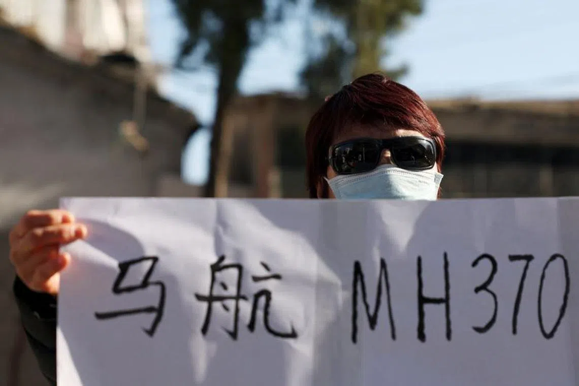 Hu Xiufang, 72, who lost her son, daughter-in-law and granddaughter, holds a sign as she speaks to the media following a court hearing on compensation for those who lost their loved ones on the Malaysia Airlines flight MH370 that went missing in 2014, in Beijing, China November 27, 2023. REUTERS/Florence Lo