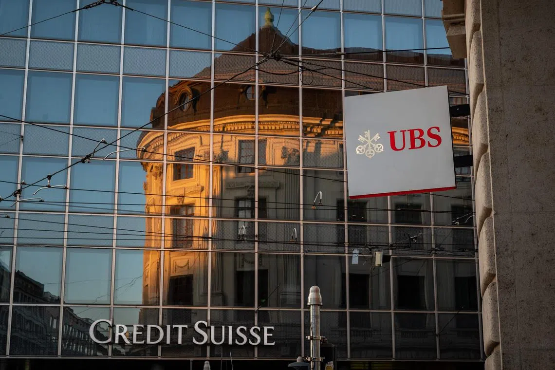 A signs of Swiss bank giant UBS bank is seen next to a sign of Credit Suisse baking in Basel, on April 4, 2023 on the eve of the general meeting of shareholders following the takeover by UBS of Credit Suisse hastily arranged by the Swiss government on March 19, 2023 to prevent a financial meltdown. (Photo by Fabrice COFFRINI / AFP)