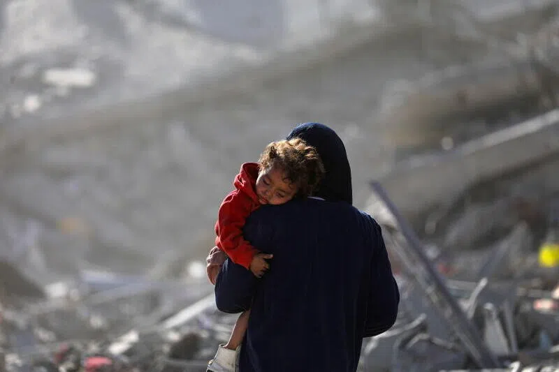 A Palestinian mother carrying her child walks among the rubble of destroyed buildings amid a ceasefire between Israel and Hamas in Gaza City, on Oct 11.